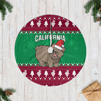 Christmas tree skirt with green and burgundy circular design, grizzly bear with Santa hat.