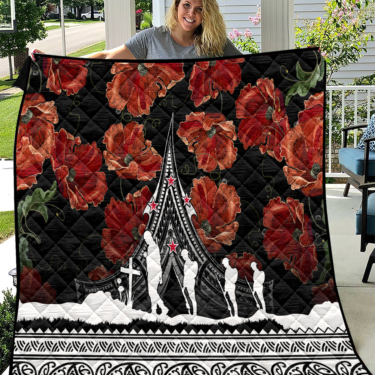 Black quilt with red poppies and Polynesian-style pattern border, featuring a white monument design