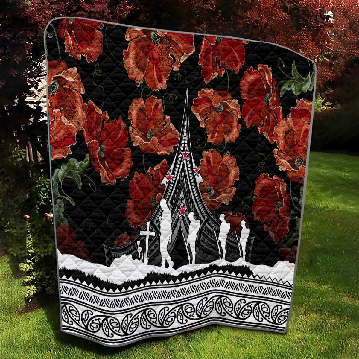 Black quilt featuring red poppies, white monument-and-figure design, and ornate Polynesian border