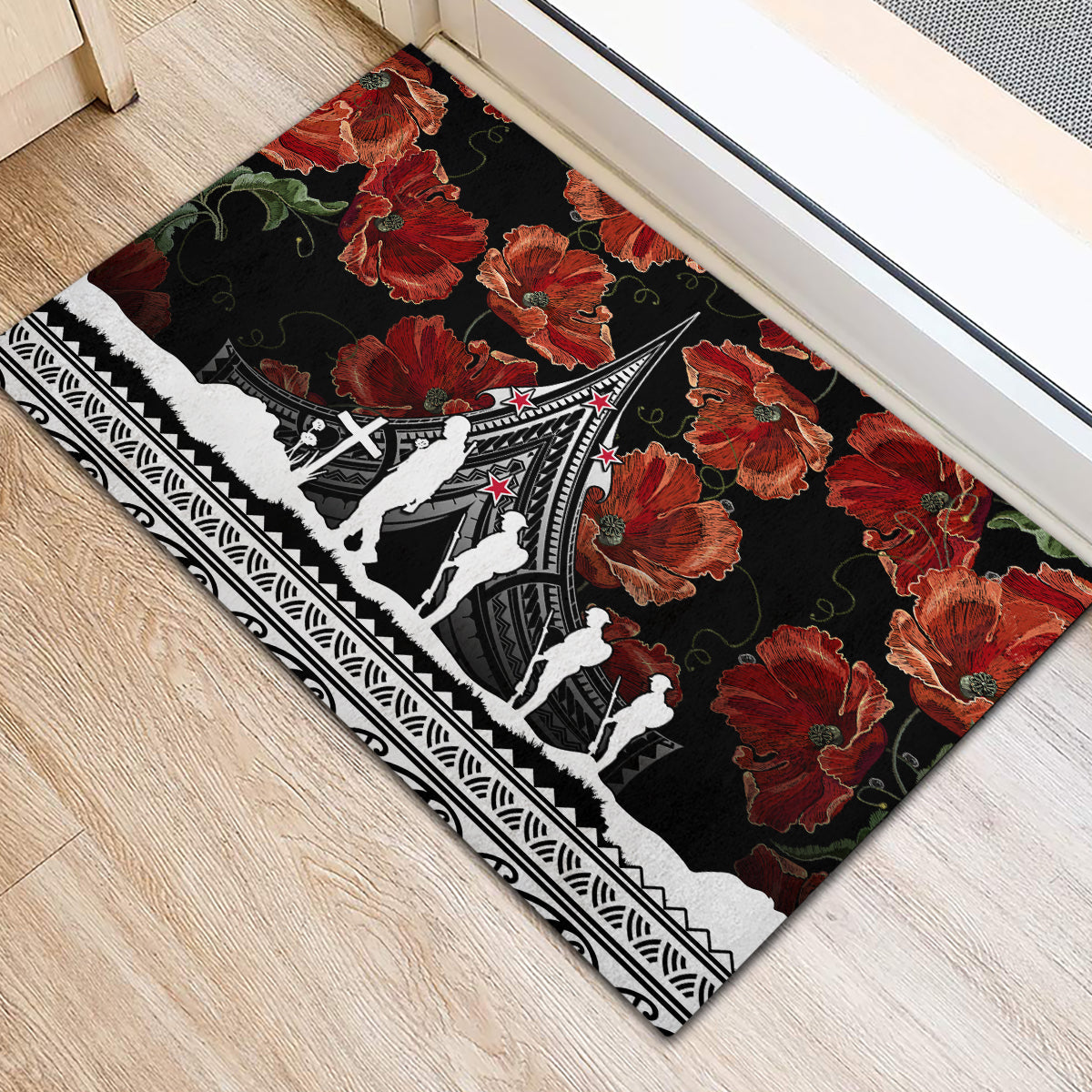 Black rubber doormat showing poppies and white figures on Polynesian border