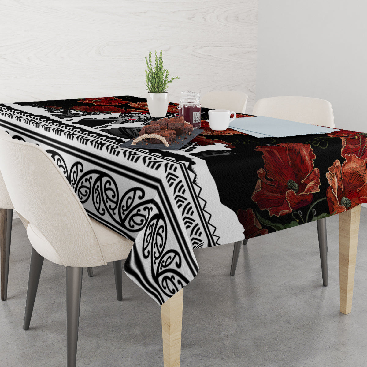 Black tablecloth with red poppies and white geometric border, draped over table edge