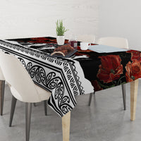 Black tablecloth with red poppies and white geometric border, draped over table edge