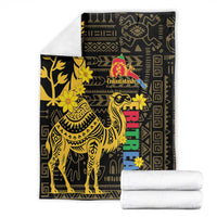 Folded black blanket with gold camel and floral pattern, Enkutatash logo and multicolor blocks