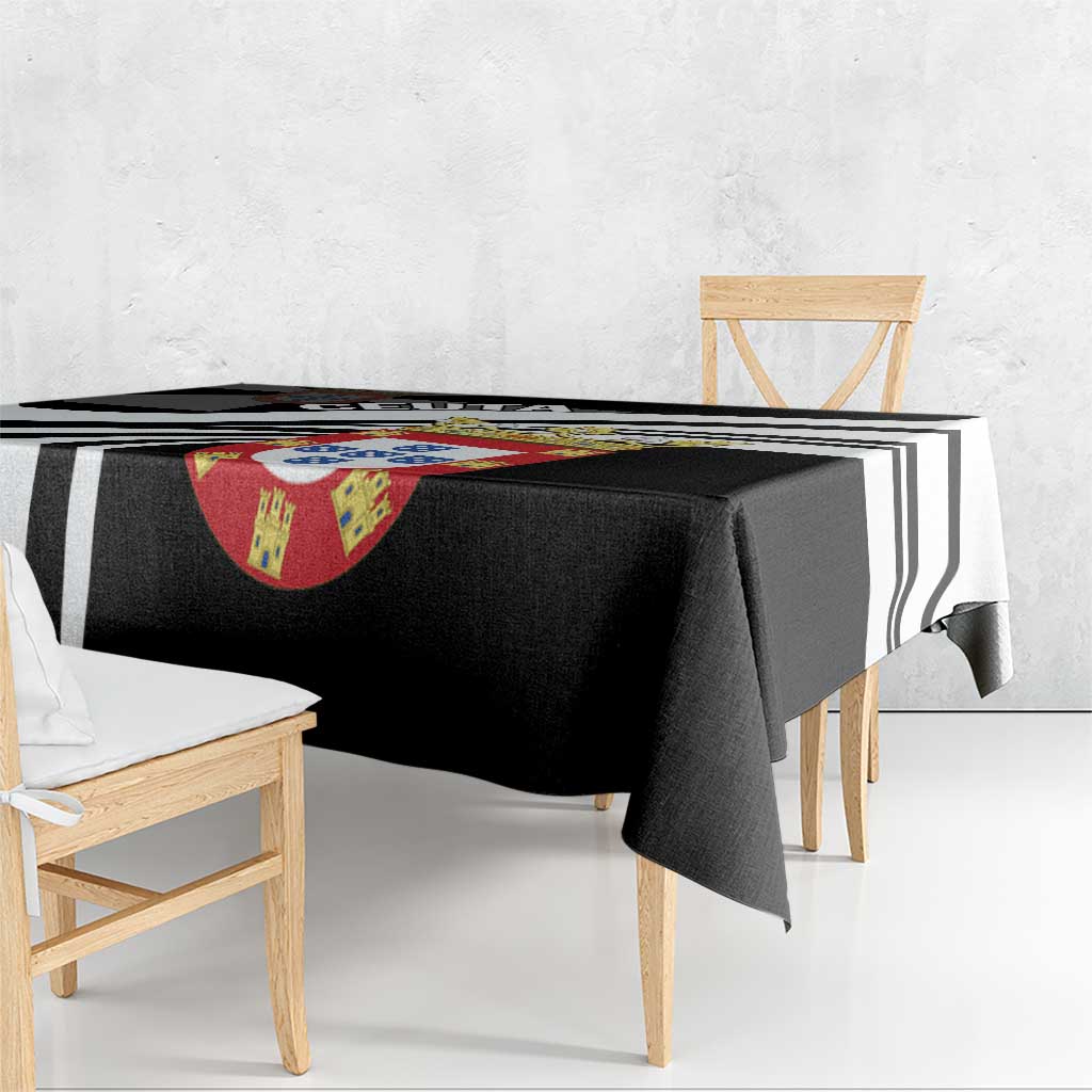 Black tablecloth with diagonal black-and-white stripes and crest motif, draped on table.
