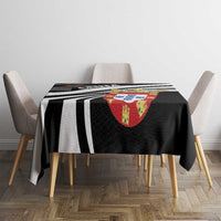 Black tablecloth on dining table featuring bold black-and-white stripes and crest emblem.