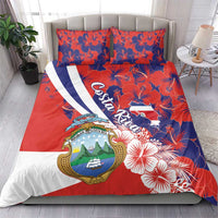 Costa Rica bedding set on bed with red hibiscus motif, crest emblem, and large script