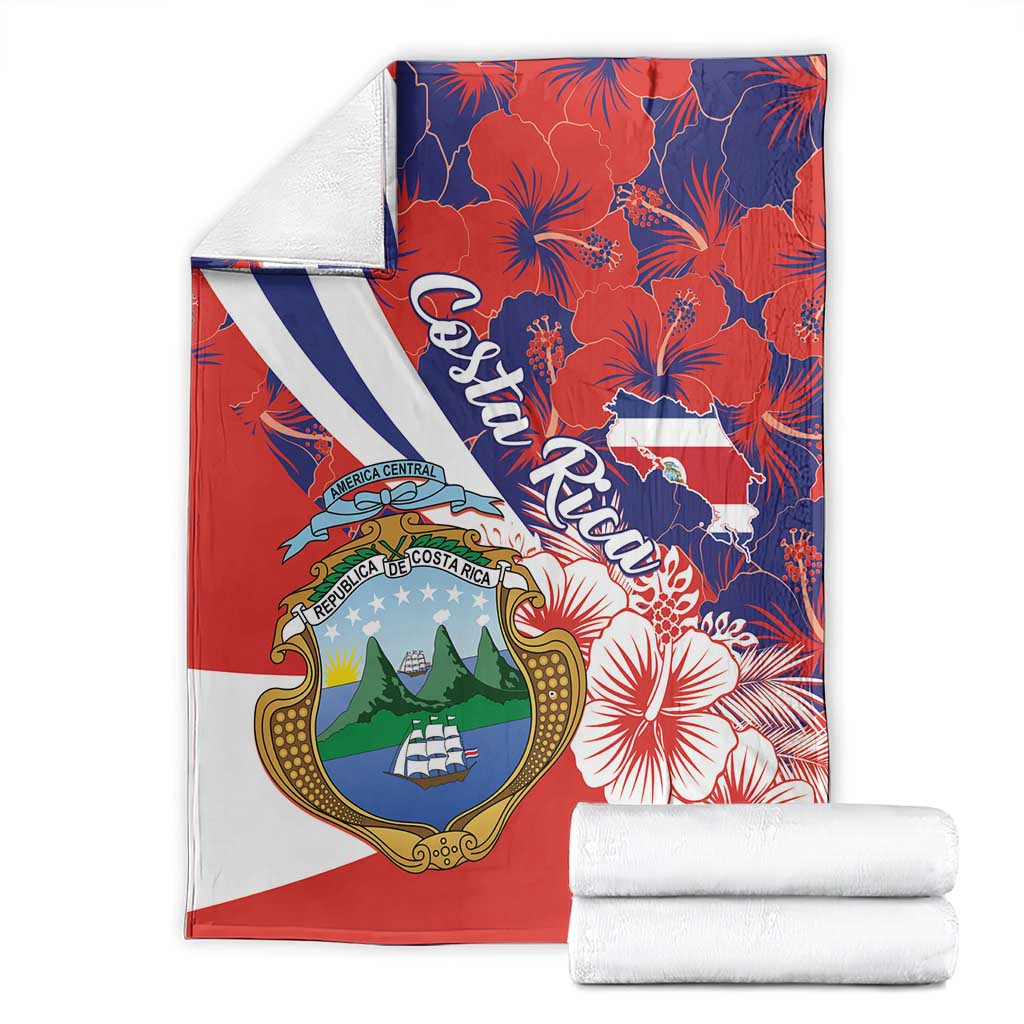 Folded red blanket featuring Costa Rica coat of arms, hibiscus pattern, and white-blue diagonal