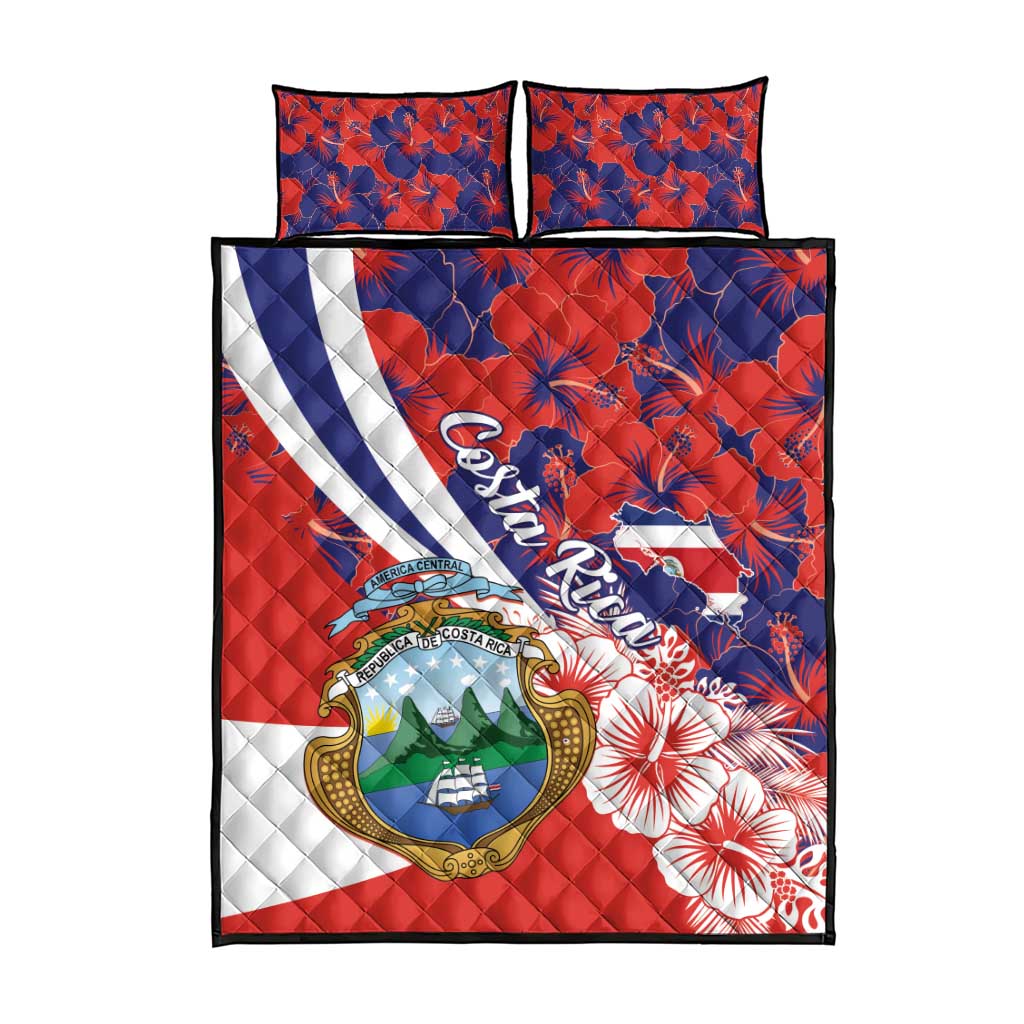 Red quilt bed set with coat of arms, blue hibiscus flowers, and two matching pillows