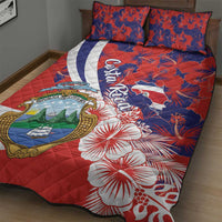 Red quilt bed set detail with coat of arms, white-and-blue striped band, hibiscus
