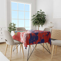 Red and blue hibiscus tablecloth over dining table with gray chairs