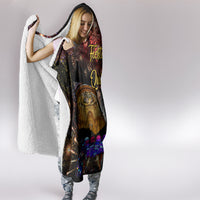 Hooded blanket with sherpa white reverse lining peeking from a black printed cover