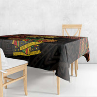 Black Kwanzaa tablecloth with bold geometric corner print and 'Happy Kwanzaa' banner.