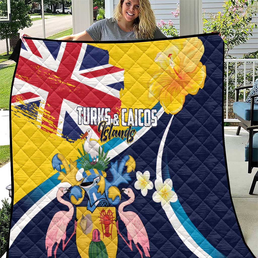 Navy quilt blanket with yellow panel, Turks & Caicos coat of arms and tropical flowers.