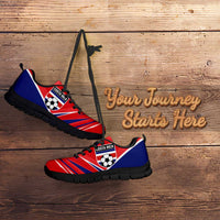 Red and blue soccer sneakers with black sole, angled on wooden surface