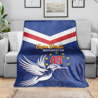 Blue independence day blanket with red-and-white chevrons, dove and stars, spread on a sofa