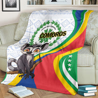 Comoros flag-themed blanket on bed with lemur character, COMOROS logo, and curved color stripes.