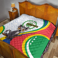 Comoros flag quilt laid on a bed with cartoon lemur holding text badge center