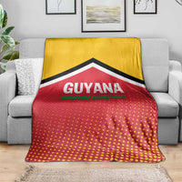 Guyana cricket blanket on gray sofa, yellow top and red dotted design with black chevron.