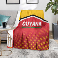 Guyana cricket blanket over gray chair, yellow-red dotted pattern with black/white chevron stripes.