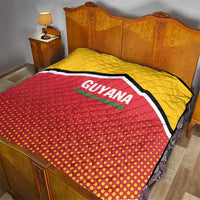 Quilt on a bed with yellow upper section, red dotted lower section, and GUYANA logo