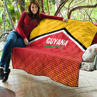 Yellow and red quilt held out outdoors, featuring black trim and GUYANA logo