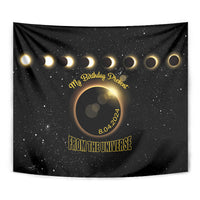 Black eclipse tapestry with gold halo, small date marks, and 'From the Universe' title