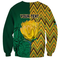 Dark green personalized sweatshirt back with protea flower, zigzag panels, and 'YOUR TEXT'