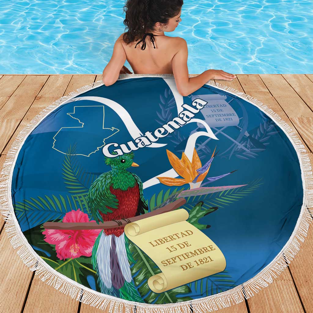 Blue round beach blanket with white fringe, Guatemala title and quetzal bird among leaves