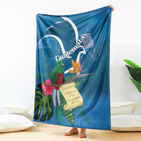 Blue tropical throw blanket hanging on bed with quetzal, flowers, and Guatemala banner