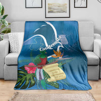 Blue tropical throw blanket on couch with quetzal, flowers, and Guatemala banner