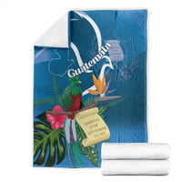 Blue tropical throw blanket with quetzal and Guatemala banner; folded with rolled towels