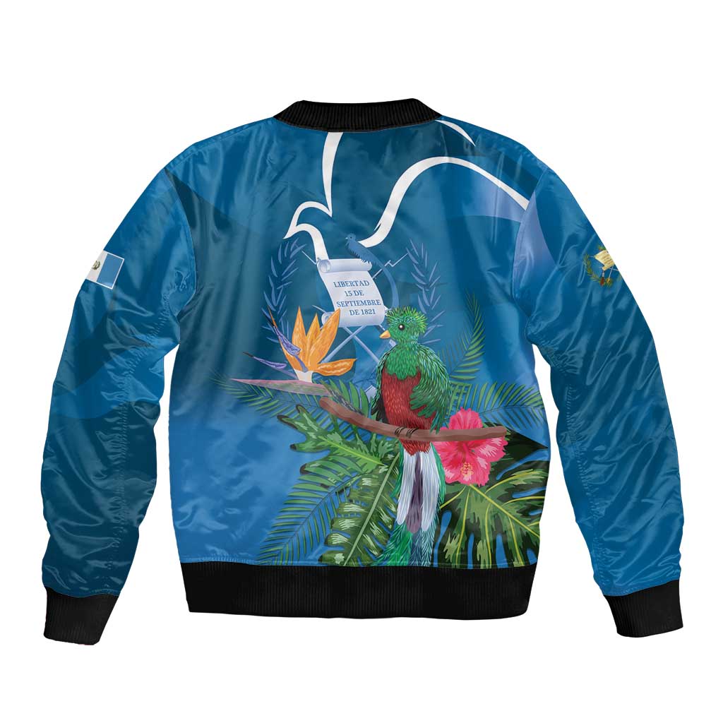 Blue bomber jacket back with tropical quetzal, leaves, and flowers; ribbed cuffs and hem