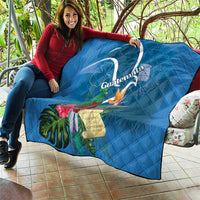 Blue quilt blanket spread out outdoors, showing Quetzal and tropical flower print