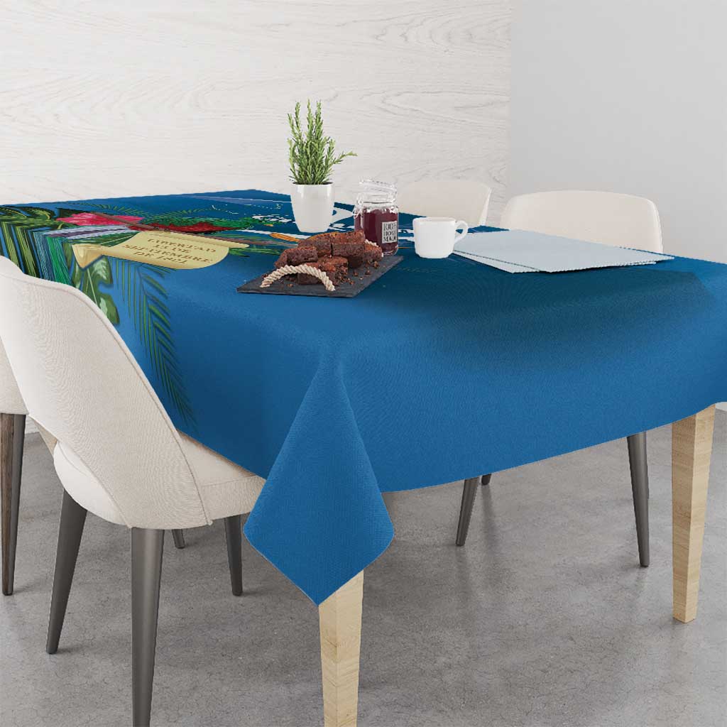 Blue tablecloth with tropical leaf print, draped on dining table with decorative centerpiece items.