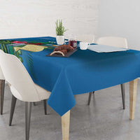 Blue tablecloth with tropical leaf print, draped on dining table with decorative centerpiece items.