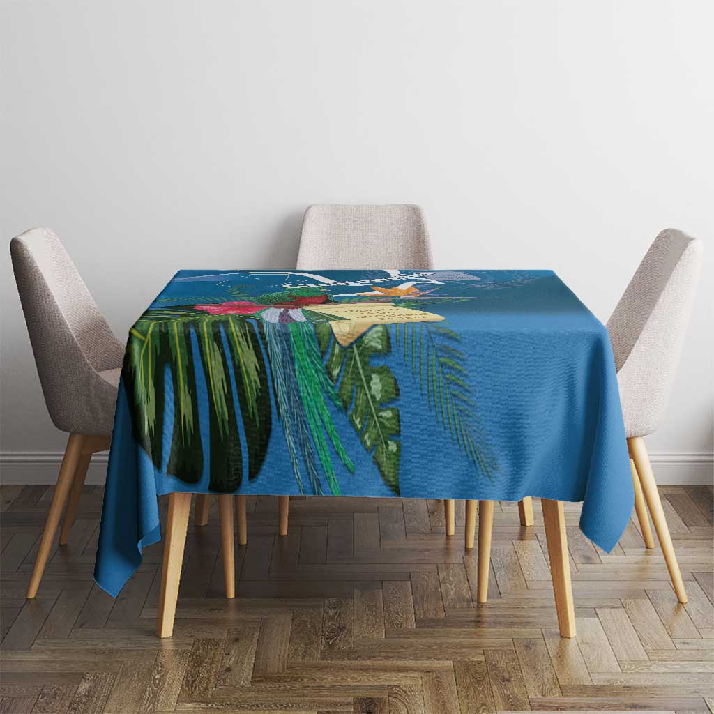 Blue tropical tablecloth with bold leaf and bird motifs, neatly laid on dining table.