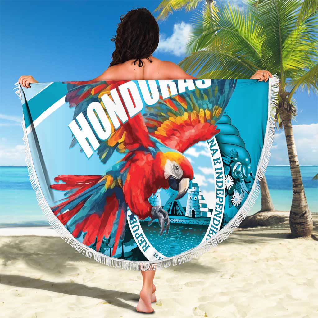 Round blue beach blanket with macaw design and white fringe, held up on the sand