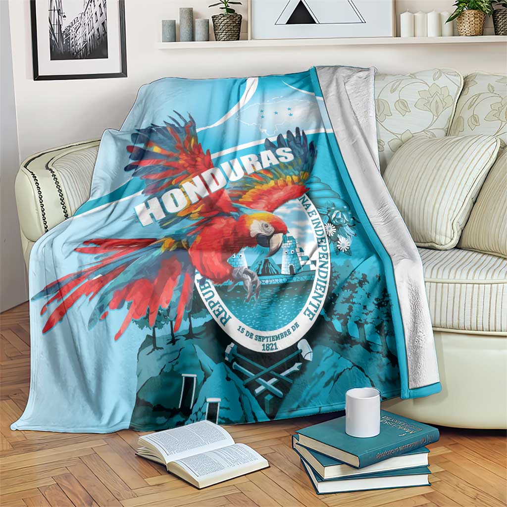 Sky blue throw blanket with red macaw and Honduras graphic, white curved stripe, soft edge.
