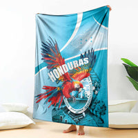 Sky blue Honduras throw blanket featuring red macaw, circular emblem, and white curved stripe.