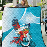 Blue and white Honduras quilt with quilted pattern and colorful macaw emblem.