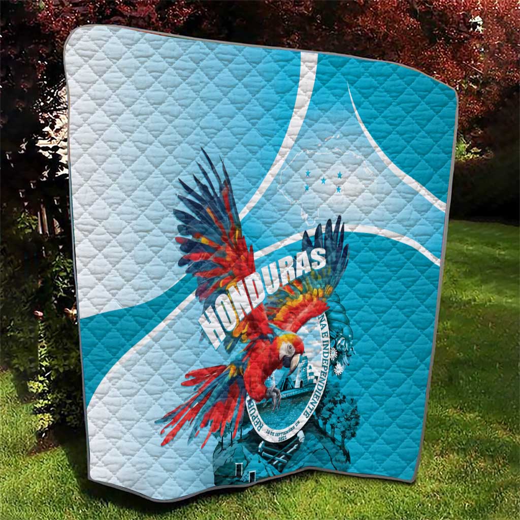 Folded blue and white Honduras quilt with central macaw graphic and quilt stitching.