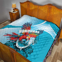 Blue and white Honduras quilt laid on a bed, featuring macaw emblem at center.