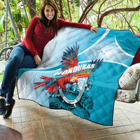 Blue and white Honduras quilt draped over sofa with colorful macaw emblem in center.