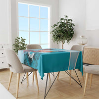 Teal-blue printed tablecloth featuring colorful emblem and macaw artwork across center