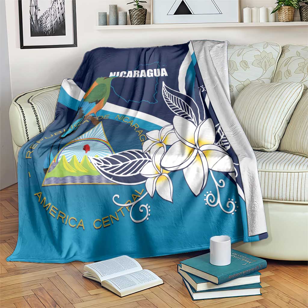 Blue Nicaragua blanket with plumeria blossoms, bird, and white flag stripes on couch