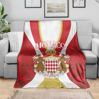 Red and white Monaco blanket with central shield crest over gray sofa