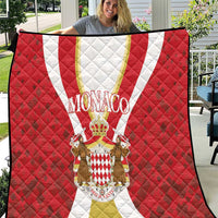 Red Monaco quilt held up, featuring white and gold center stripe and crest medallion
