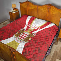 Red Monaco quilt on a bed, with white and gold center stripe and crest emblem in fabric