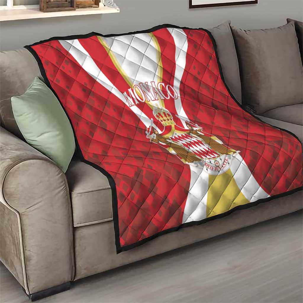 Red Monaco quilt laid on a gray sofa, with white-gold stripe and centered crest emblem