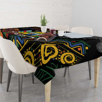 Black tablecloth with yellow, green, and blue African geometric motifs, draped over table.